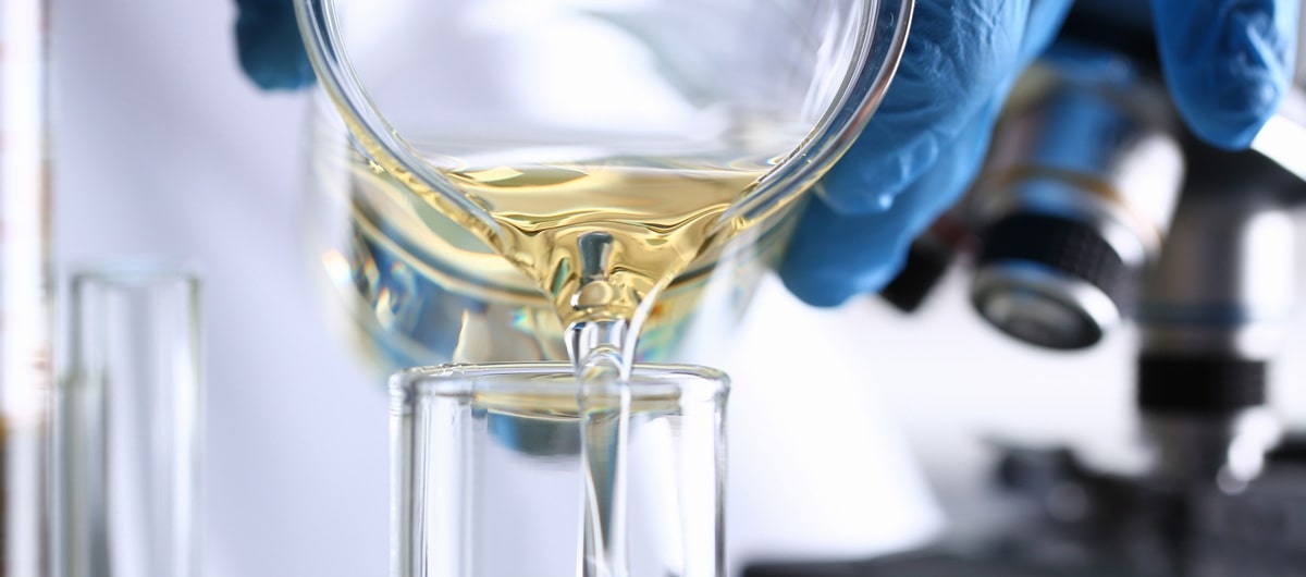 Lab pouring yellow liquid into a beaker for self-adhesive tapes